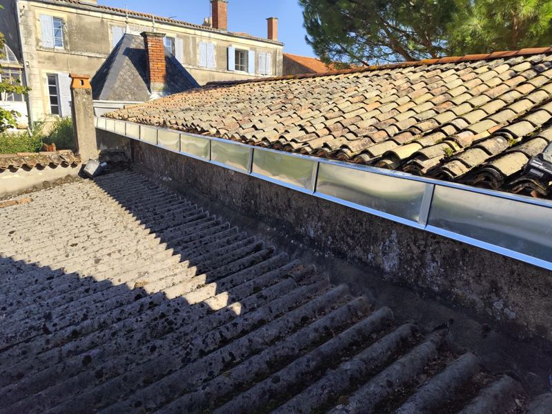 Chéneau en zinc neuf au pied d'une toiture en tuiles