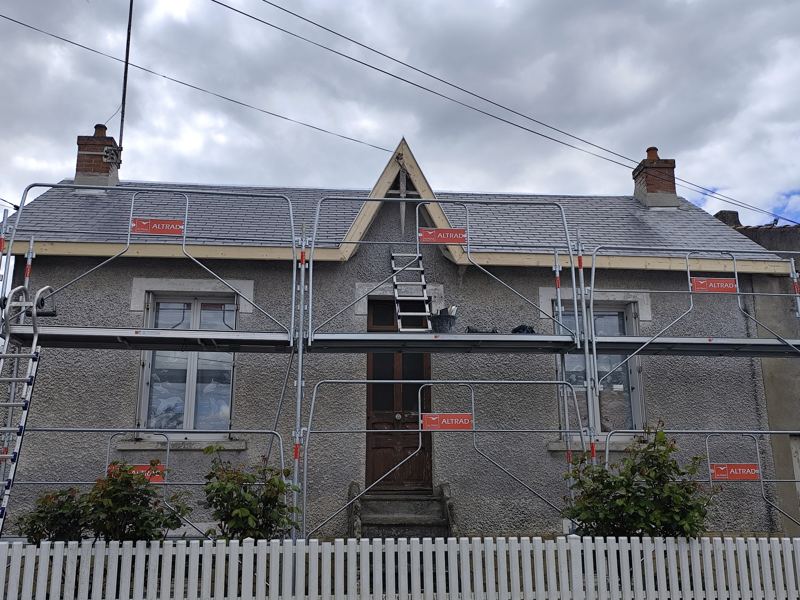 Maison entourée d'un échafaudage avec garde-corps pendant la réfection de sa toiture